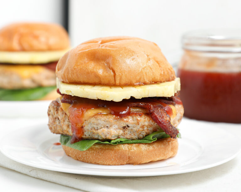 BBQ Hawaiian chicken burger with bacon, pineapple, cheese, lettuce, and barbecue sauce on a toasted bun