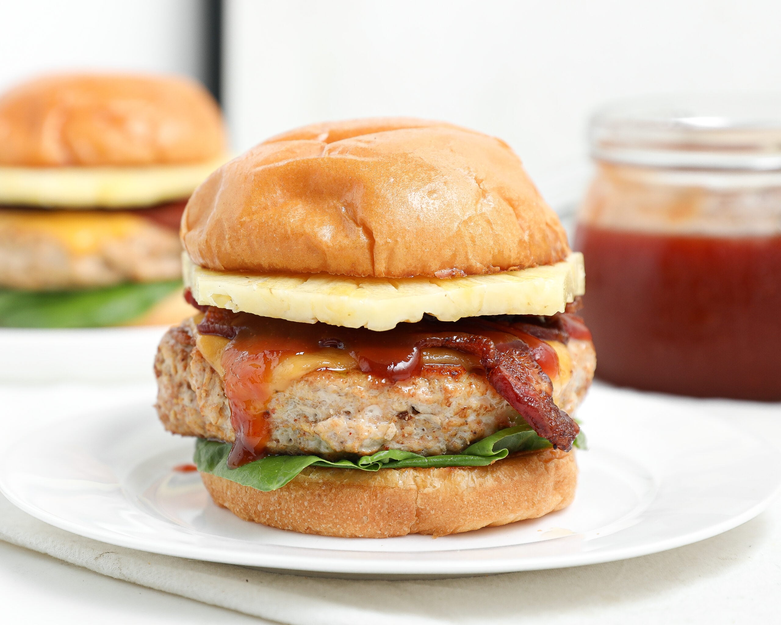 BBQ Hawaiian chicken burger with bacon, pineapple, cheese, lettuce, and barbecue sauce on a toasted bun