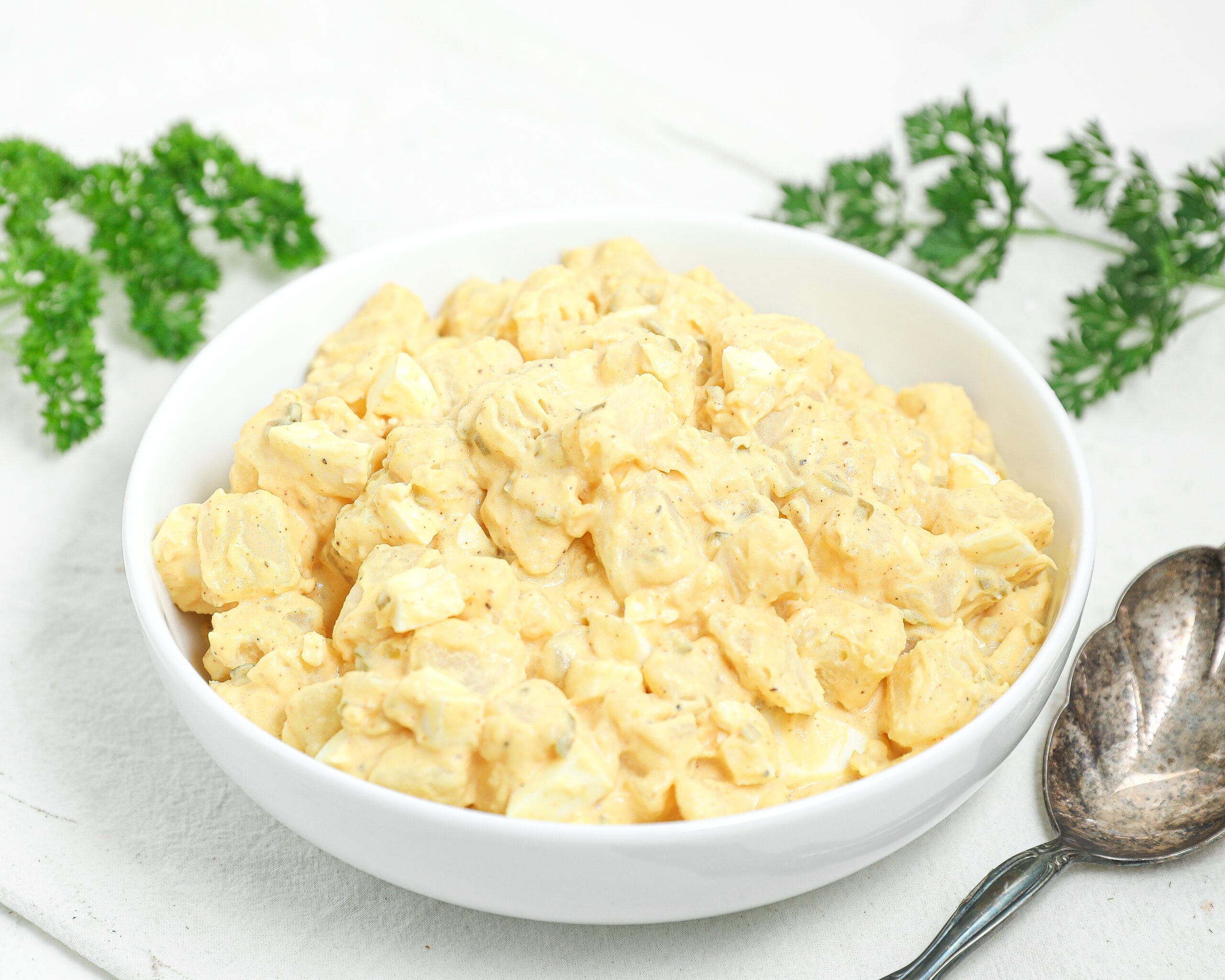 Creamy Southern potato salad with eggs, relish, and mustard dressing served in a white bowl.