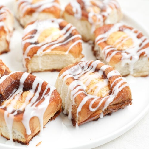 Cinnamon Roll Cheesecake Sliders with cream cheese filling, cinnamon sugar topping, and sweet glaze on a white plate.