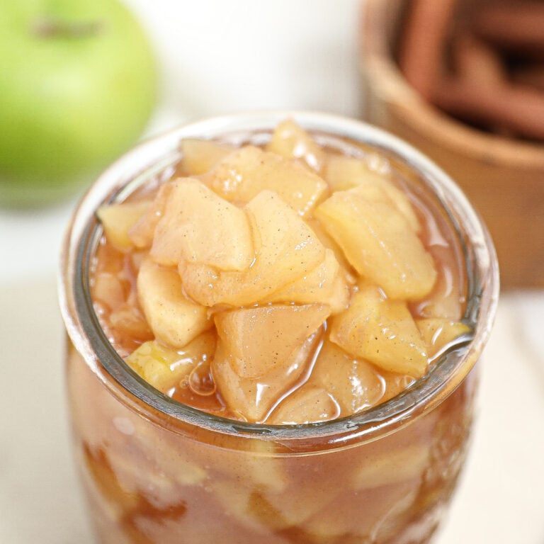 Homemade apple pie filling in small glass jar.