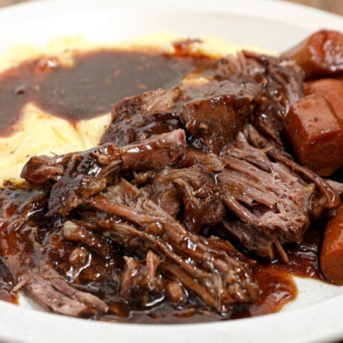 Beef pot roast on plate with carrots.