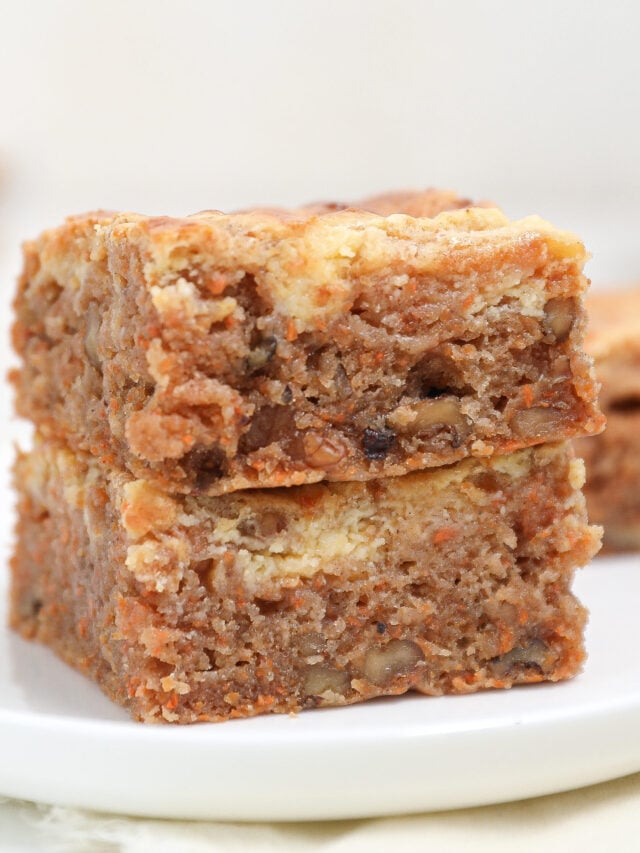 Slices of carrot cake brownies stacked on white plate.