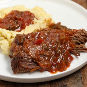 This fork tender oven brisket is braised low and slow with beef stock, tomatoes, peppers, onion, and celery, then finished with a rich homemade gravy.