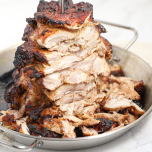 Slice chicken shawarma stackend on white plate.