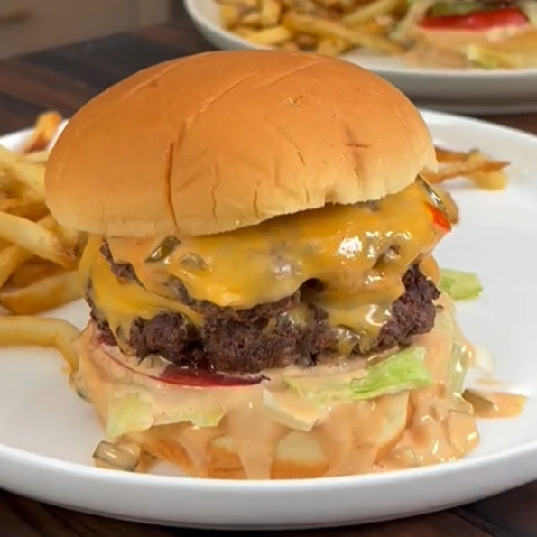 A copycat In N Out cheeseburger sitting on a plate with French fries.