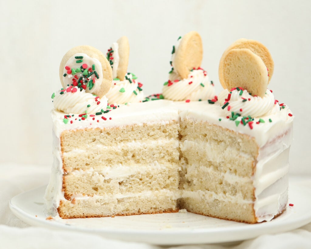 Slice of sugar cookie dough cake with sprinkles and vanilla frosting