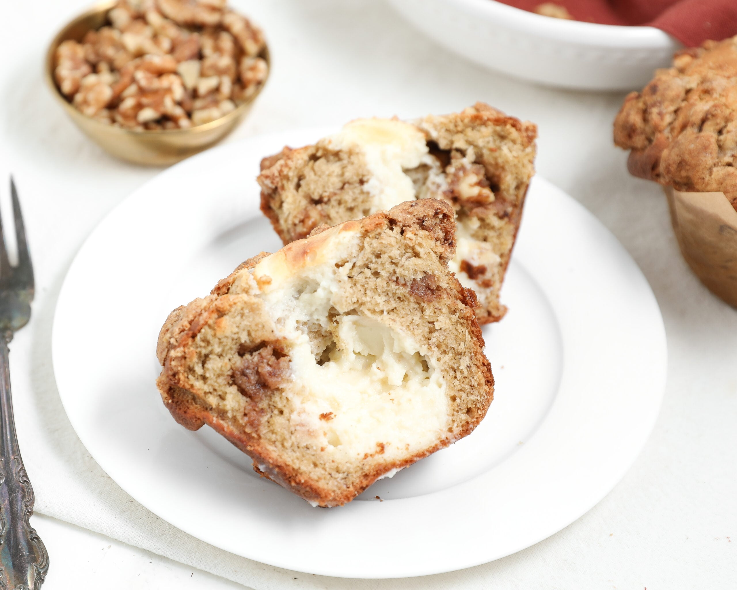Banana bread coffee cake muffins with cream cheese filling and cinnamon swirl, cut open on a white plate