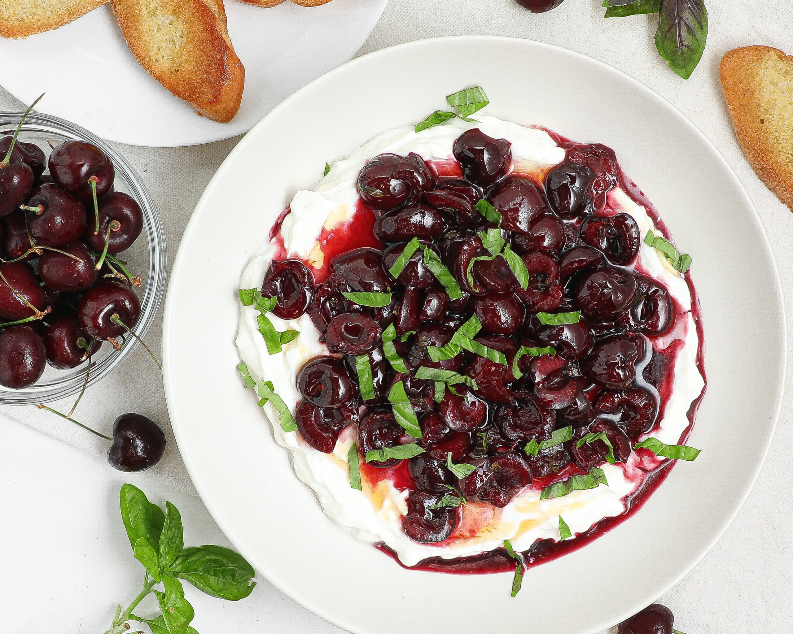 Creamy whipped feta dip topped with roasted cherries, fresh basil, and hot honey served with crostini.