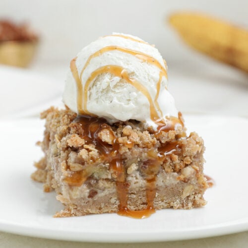 Banana Foster Cheesecake Crumble Bars with caramelized bananas, oat crumble topping, and caramel sauce.