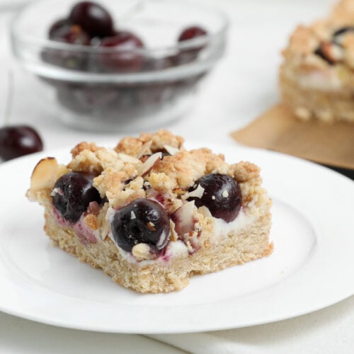 Cherry Almond Cheesecake Crumble Bars topped with buttery almond crumble and fresh cherries.