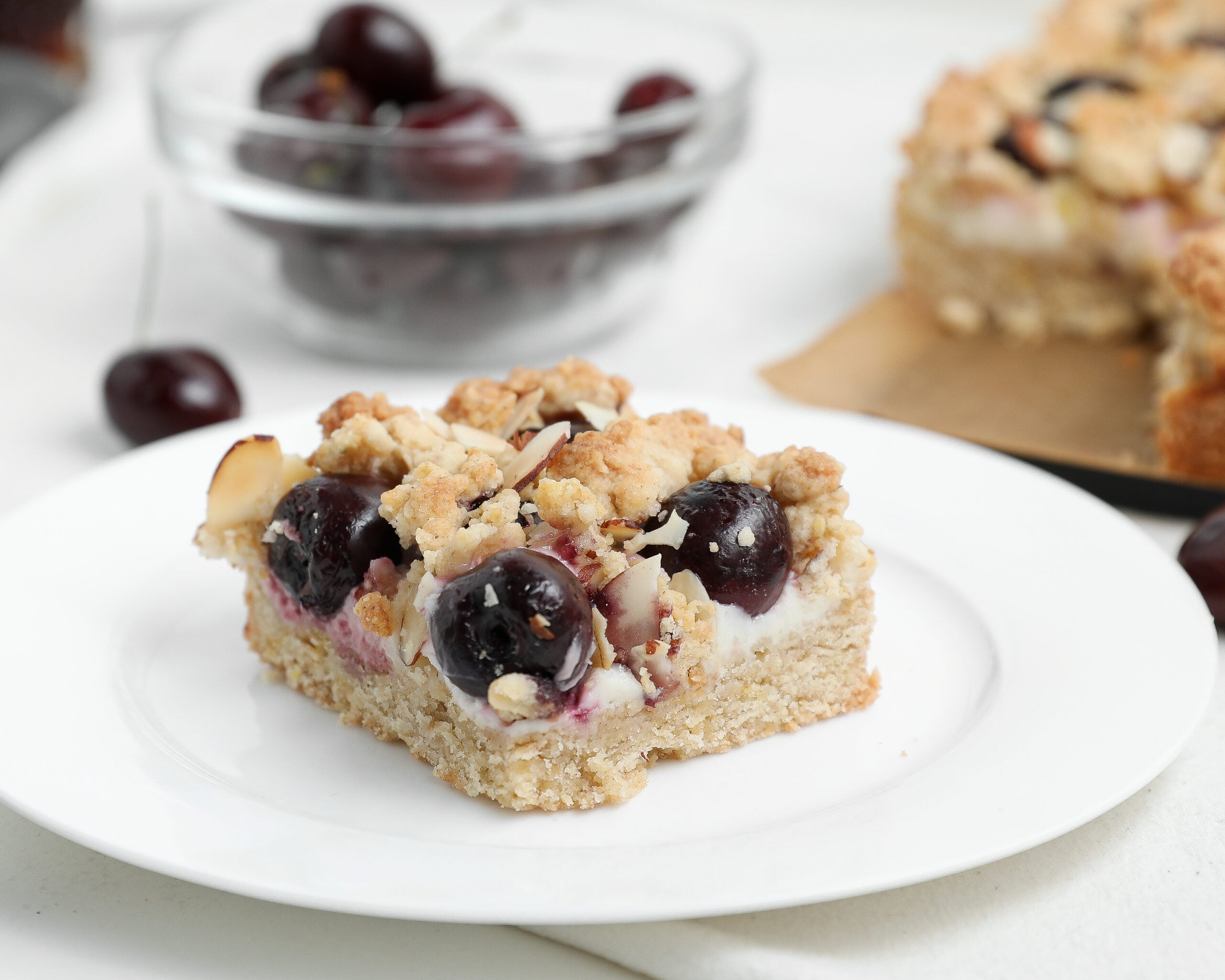 Cherry Almond Cheesecake Crumble Bars topped with buttery almond crumble and fresh cherries.
