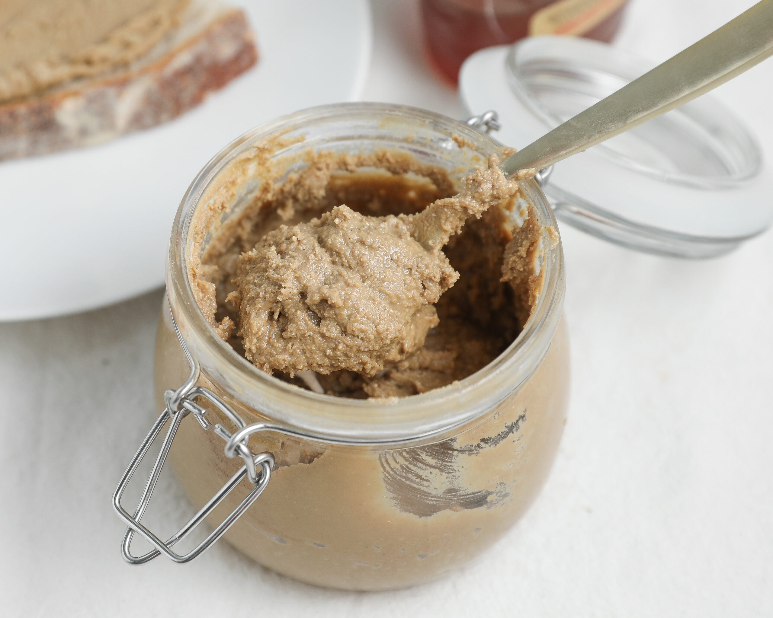 Homemade cinnamon honey sunflower seed butter in a glass jar with a spoon.