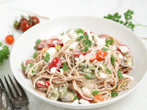 Easy Creamy Spaghetti Pasta Salad with tomatoes, feta cheese, olives, parsley, and creamy Italian dressing in a serving bowl.