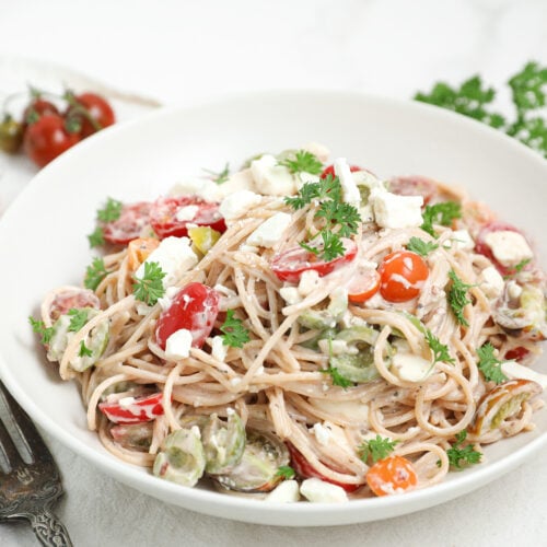 Easy Creamy Spaghetti Pasta Salad with tomatoes, feta cheese, olives, parsley, and creamy Italian dressing in a serving bowl.