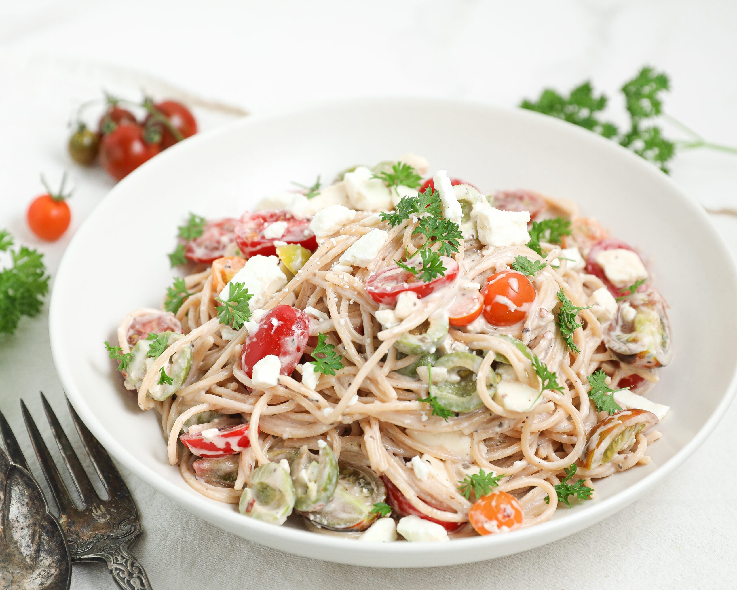 Easy Creamy Spaghetti Pasta Salad with tomatoes, feta cheese, olives, parsley, and creamy Italian dressing in a serving bowl.