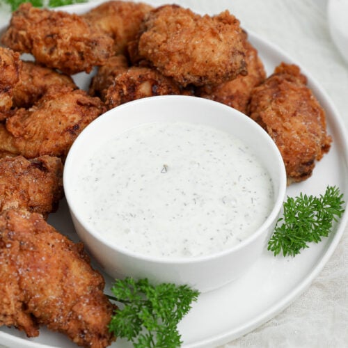 Small bowl filled with creamy homemade pickle ranch made with dill pickles and fresh herbs served as a dipping sauce.