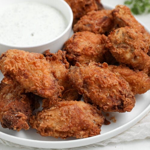 Crispy Fried Chicken Wings served on a platter with a crunchy golden coating and homemade dill pickle ranch dressing for dipping.