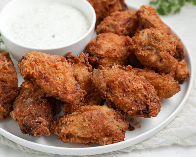 Crispy Fried Chicken Wings served on a platter with a crunchy golden coating and homemade dill pickle ranch dressing for dipping.