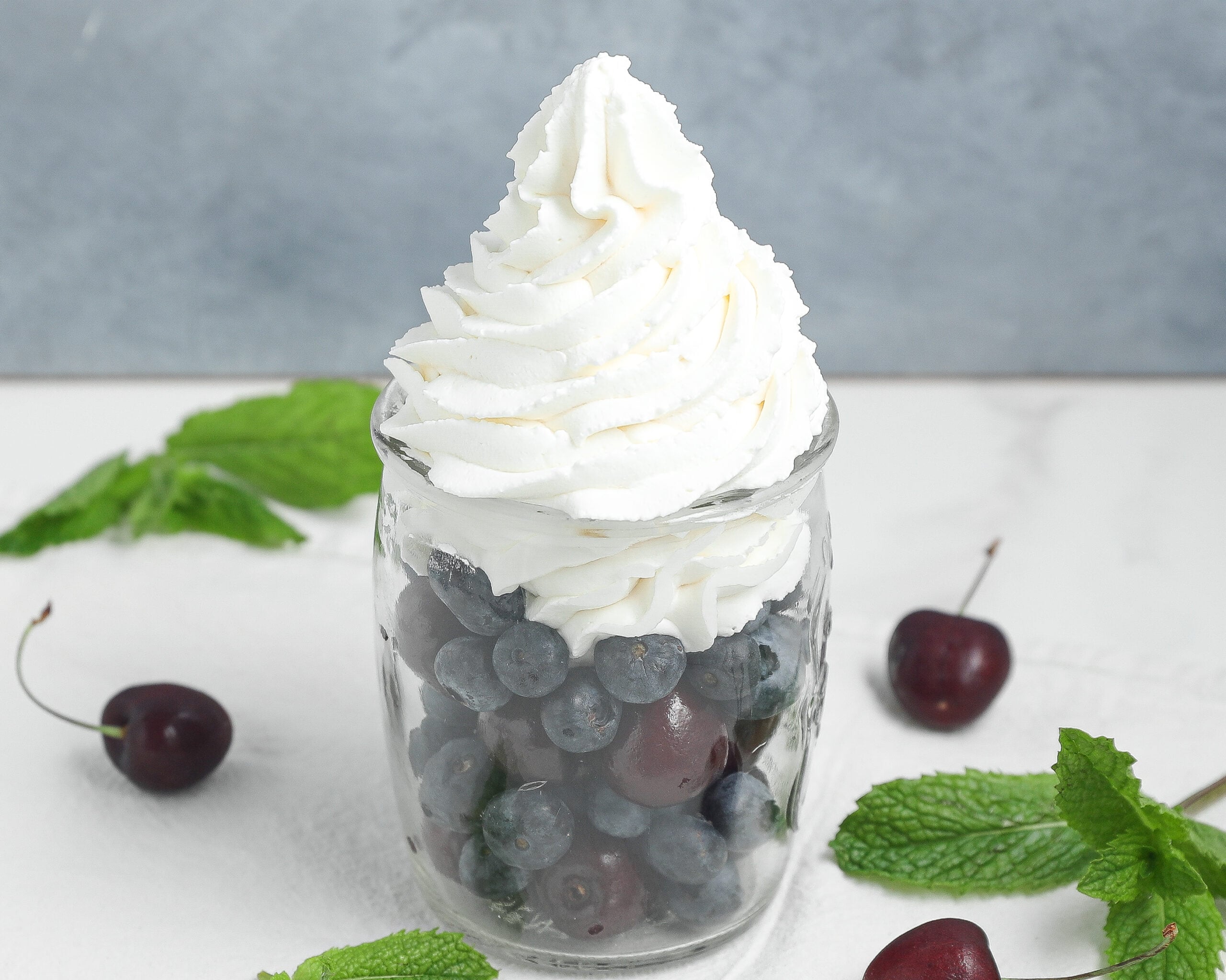 Homemade whipped cream in a glass bowl made with heavy cream, powdered sugar, and vanilla.