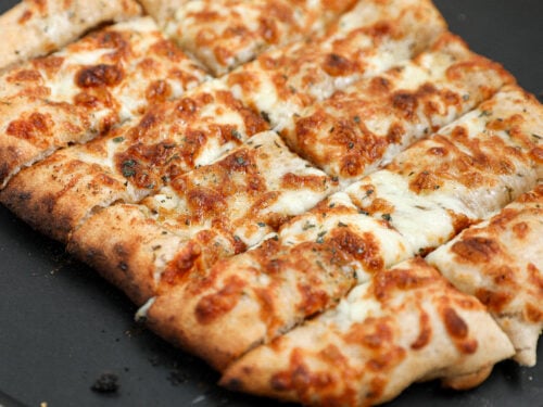 Cheesy Italian bread sticks made with sourdough pizza dough, garlic butter, and mozzarella cheese baked until golden brown and sliced into breadsticks.