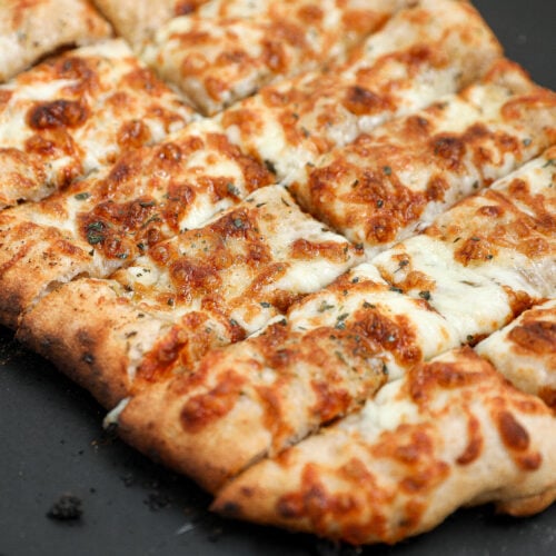Cheesy Italian bread sticks made with sourdough pizza dough, garlic butter, and mozzarella cheese baked until golden brown and sliced into breadsticks.