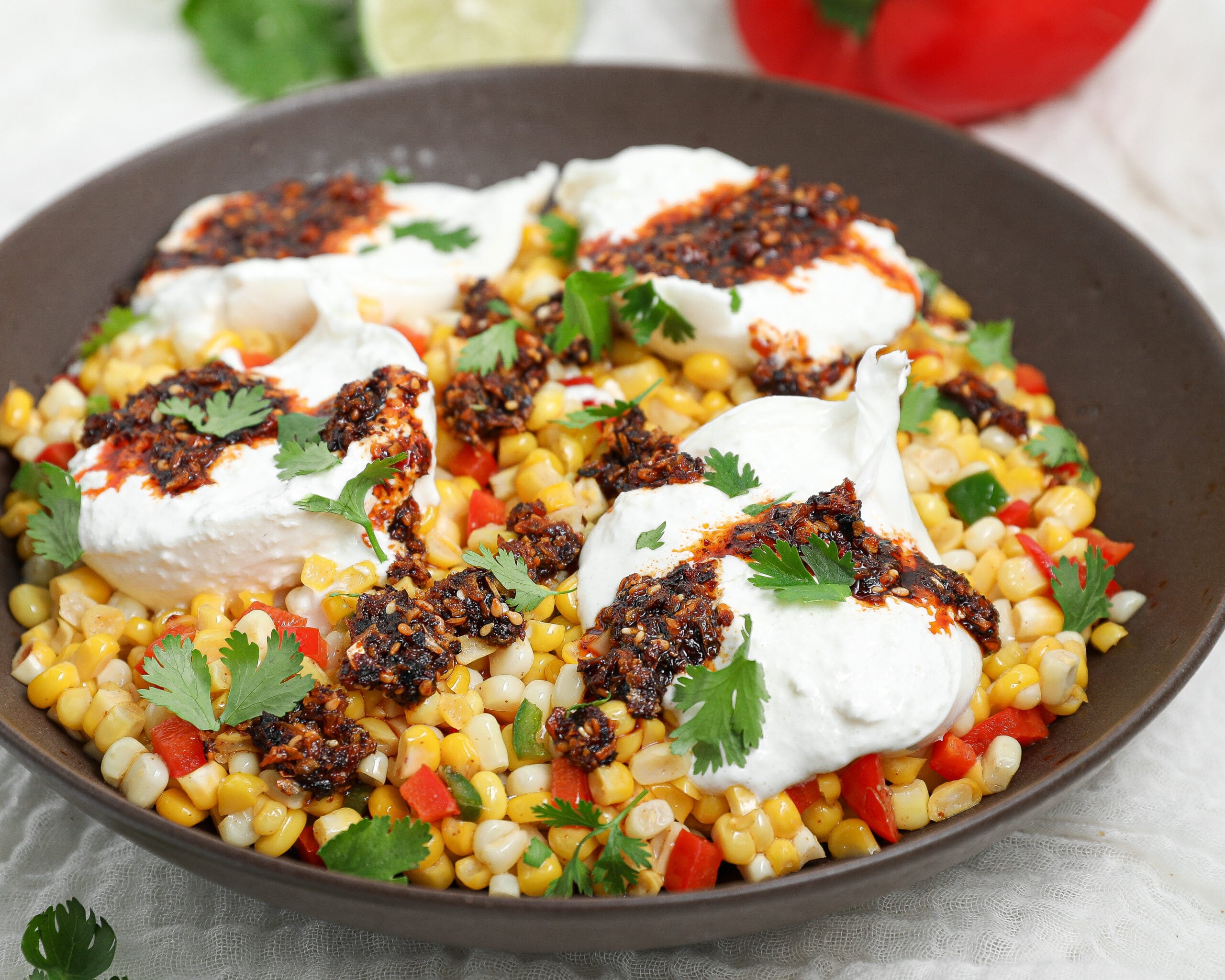 Warm Corn Burrata Dip with creamy burrata, sweet corn, peppers, crunchy garlic chili oil, fresh cilantro, and lime.