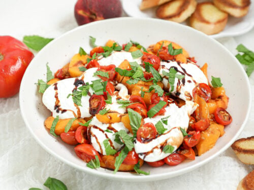 Roasted Tomato Peach Burrata Dip with roasted peaches, cherry tomatoes, creamy burrata, basil, mint, balsamic glaze, and toasted crostini.