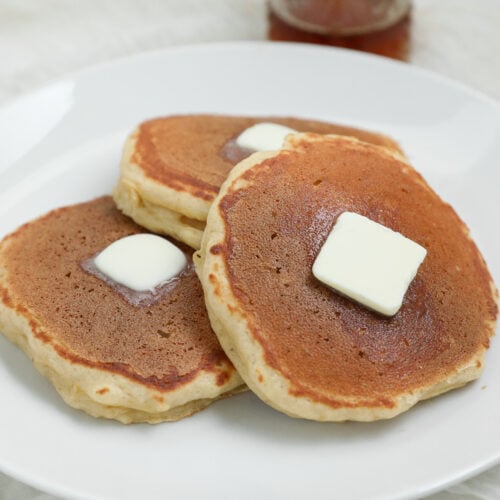 Banana Cottage Cheese Pancakes topped with melting butter on a white plate.