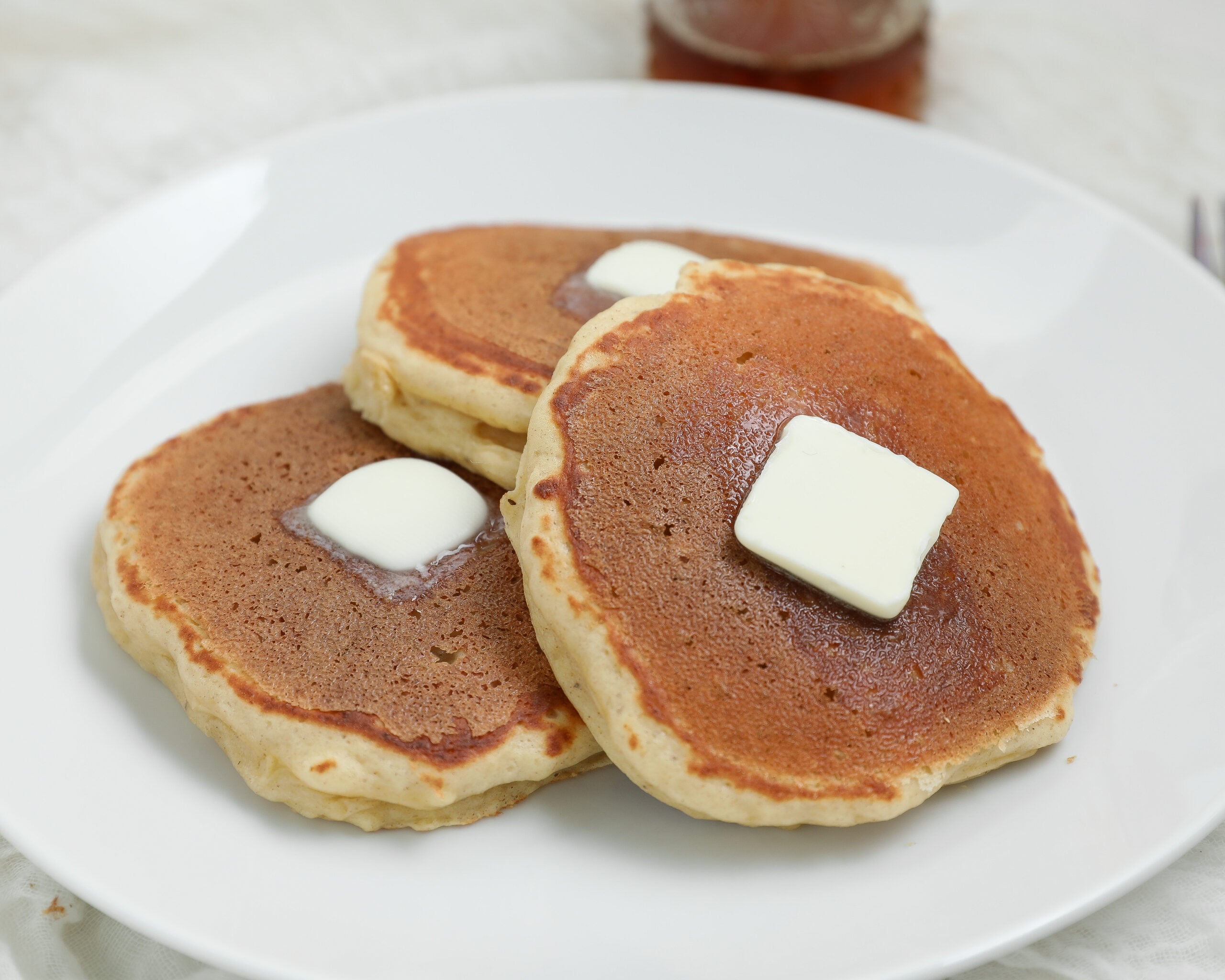 Banana Cottage Cheese Pancakes topped with melting butter on a white plate.