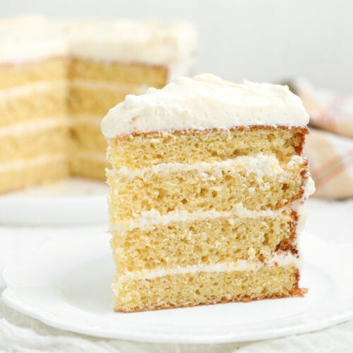 Slice of four-layer Cornbread Cake with Honey Vanilla Frosting on a white plate