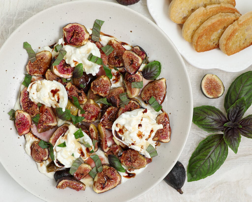 Roasted Fig Burrata Dip with fresh figs, creamy burrata, prosciutto, honey ricotta, balsamic glaze and fresh basil served with toasted bread.