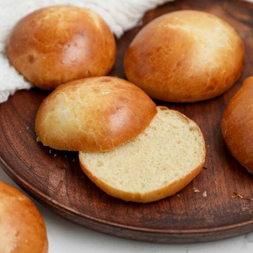 Homemade Hamburger Buns: Soft and fluffy homemade hamburger buns with golden brown tops, including one sliced open to show the tender inside.