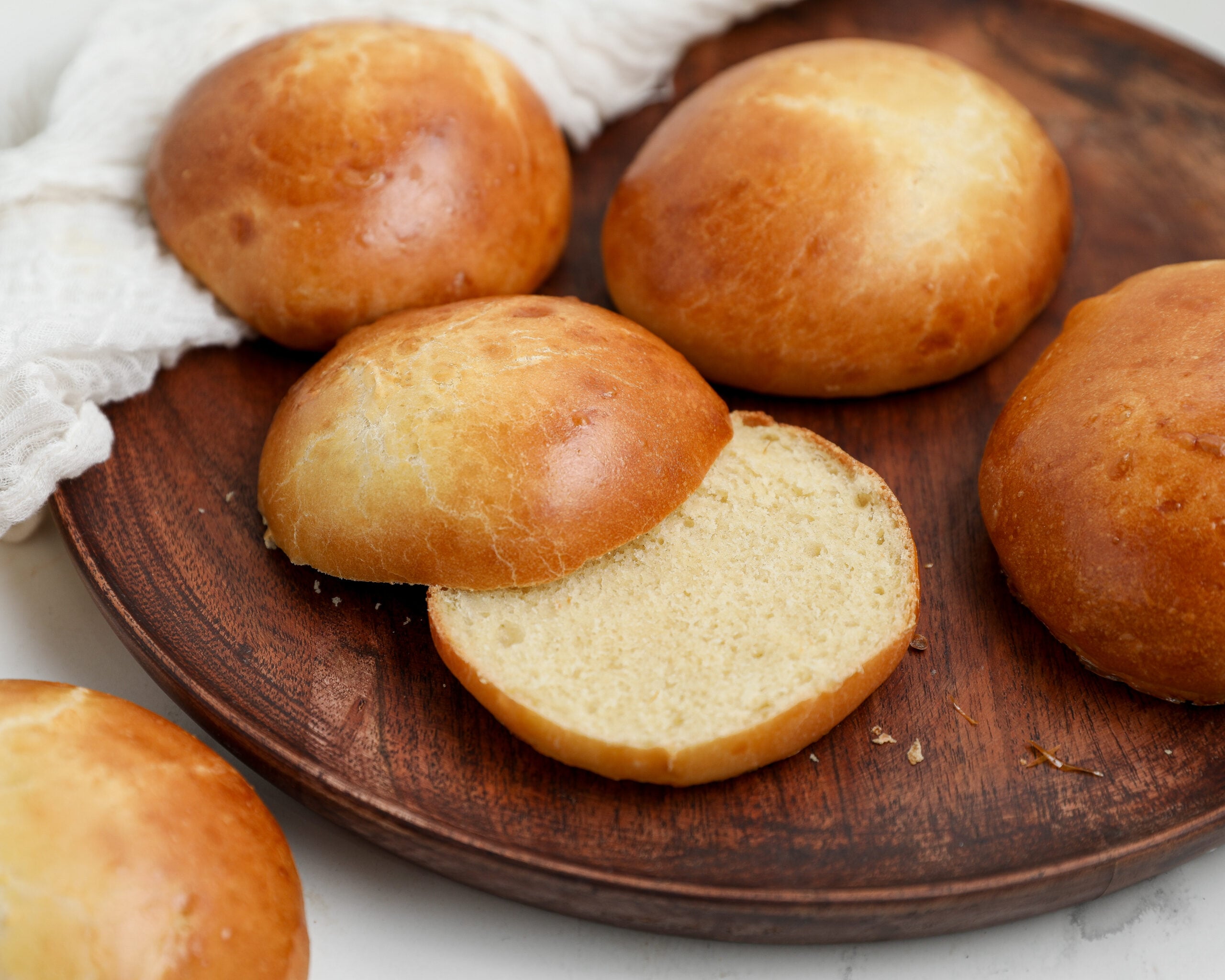 Homemade Hamburger Buns: Soft and fluffy homemade hamburger buns with golden brown tops, including one sliced open to show the tender inside.