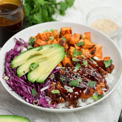 Korean BBQ Chicken Bowl with gochujang chicken, white rice, roasted sweet potatoes, shredded purple cabbage, avocado, and Korean BBQ sauce.