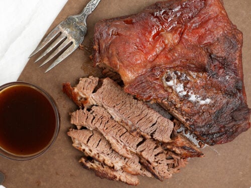Fork tender oven baked BBQ brisket sliced against the grain with BBQ sauce on the side