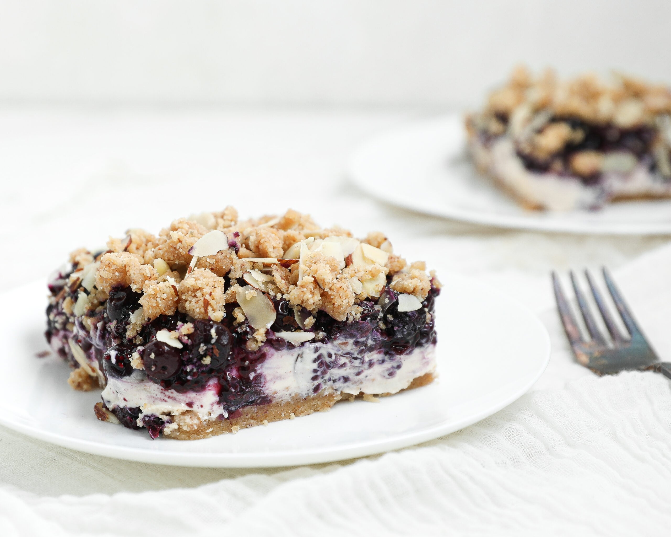 Berry Cottage Cheesecake Bars with creamy cottage cheese filling, berry chia jam, almond shortbread crust, and almond crumble topping.