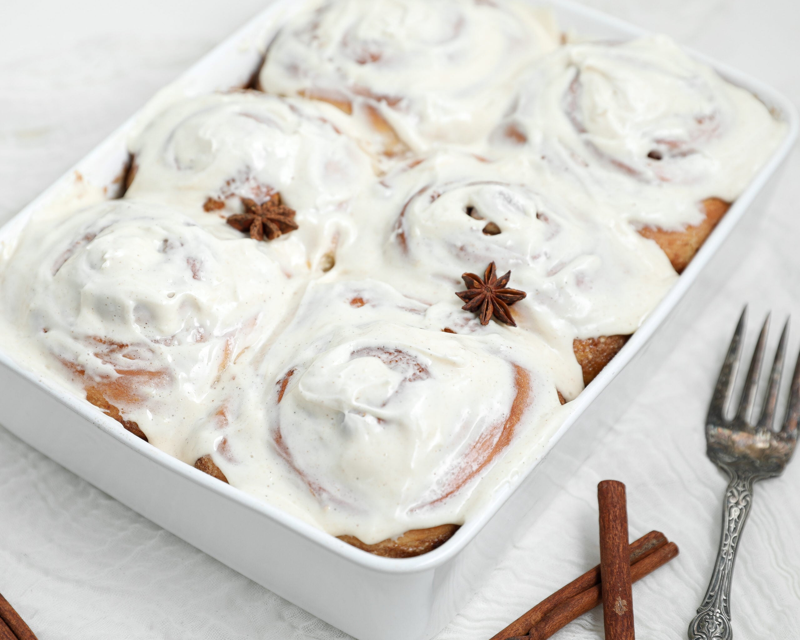 Chai cinnamon rolls with chai cream cheese frosting in a white baking dish