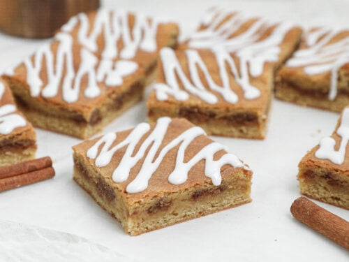 Cinnamon Roll Blondies cut into squares with a cinnamon-brown sugar filling and vanilla glaze drizzled on top.