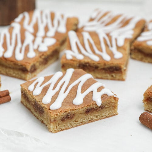 Cinnamon Roll Blondies cut into squares with a cinnamon-brown sugar filling and vanilla glaze drizzled on top.