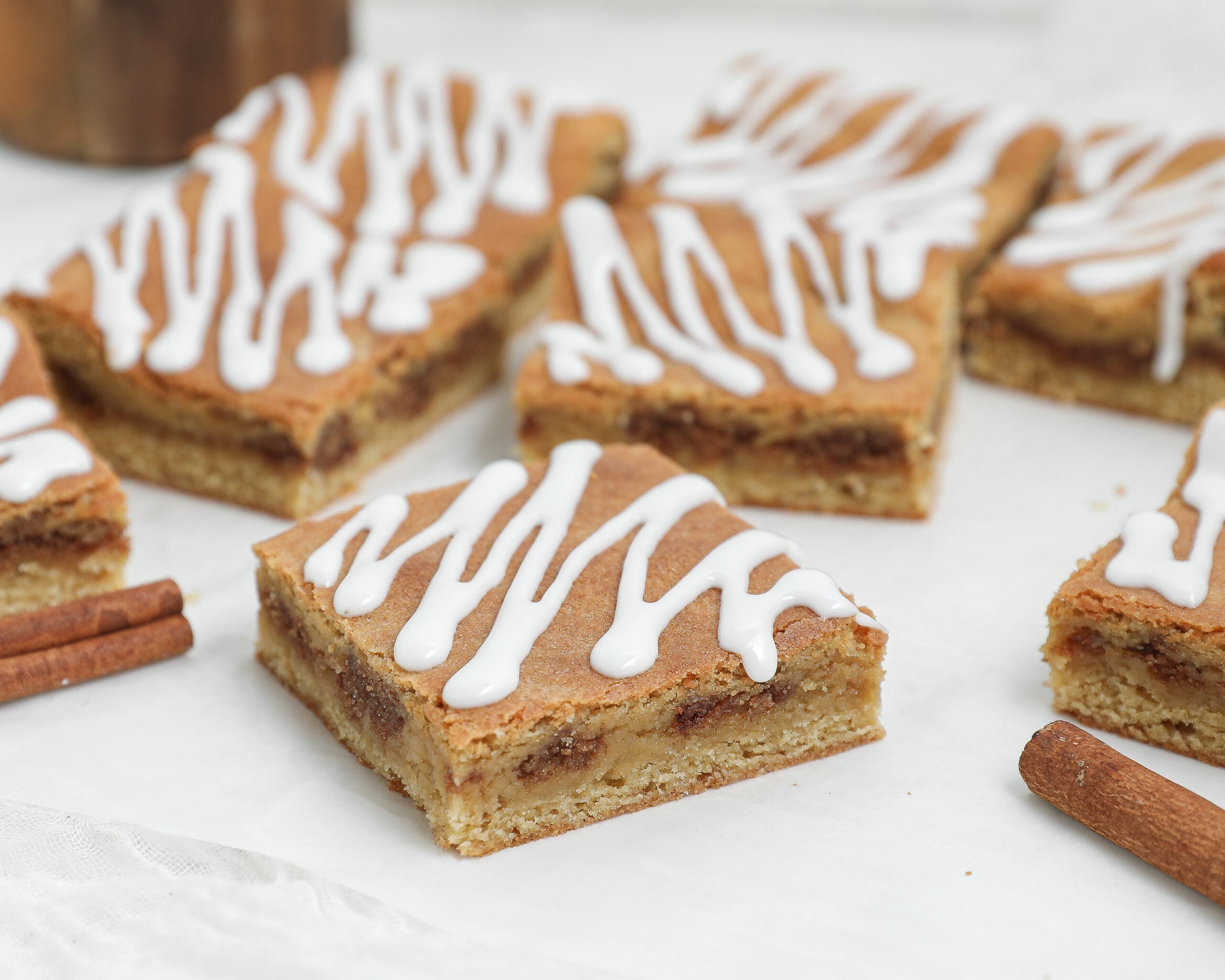 Cinnamon Roll Blondies cut into squares with a cinnamon-brown sugar filling and vanilla glaze drizzled on top.