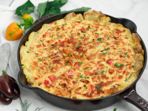 Potato crusted quiche with peppers and fresh chives baked in a cast iron skillet