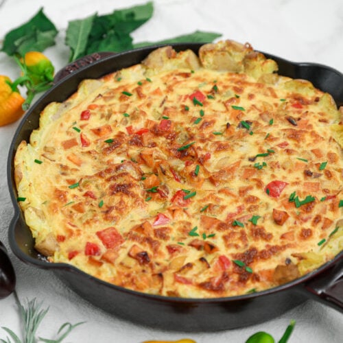 Potato crusted quiche with peppers and fresh chives baked in a cast iron skillet