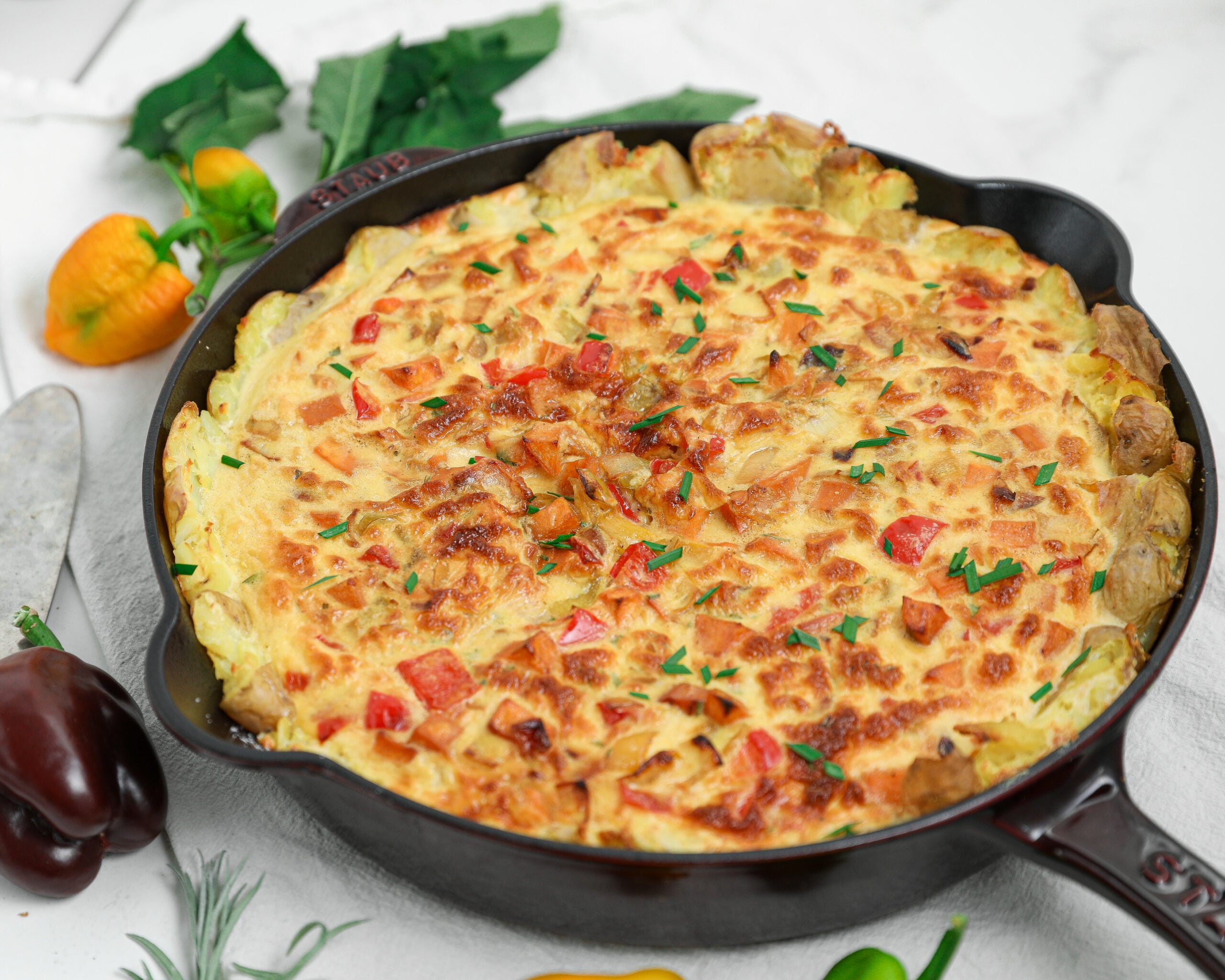 Potato crusted quiche with peppers and fresh chives baked in a cast iron skillet