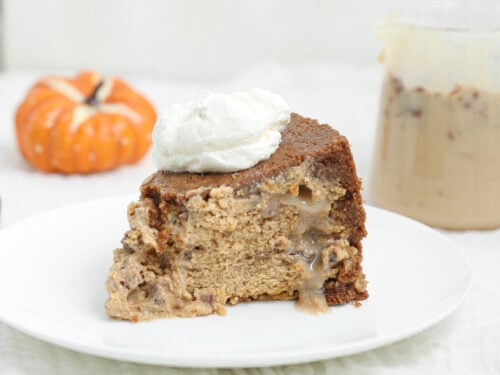 Slice of upside down pecan praline pumpkin cheesecake with a gooey pecan praline center and whipped cream