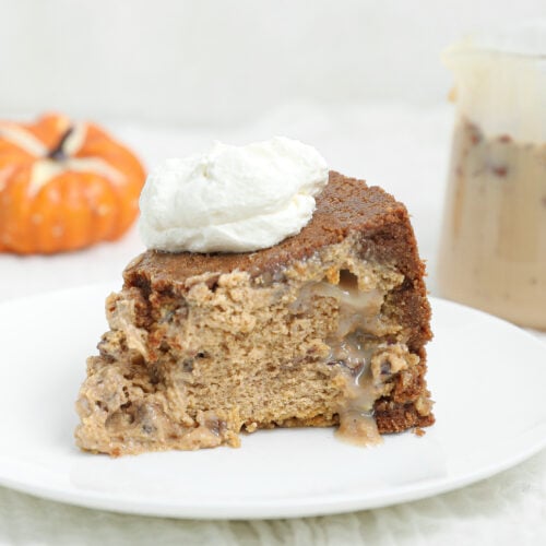 Slice of upside down pecan praline pumpkin cheesecake with a gooey pecan praline center and whipped cream