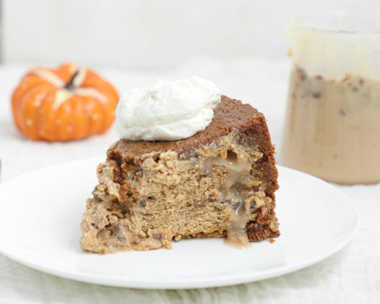 Slice of upside down pecan praline pumpkin cheesecake with a gooey pecan praline center and whipped cream