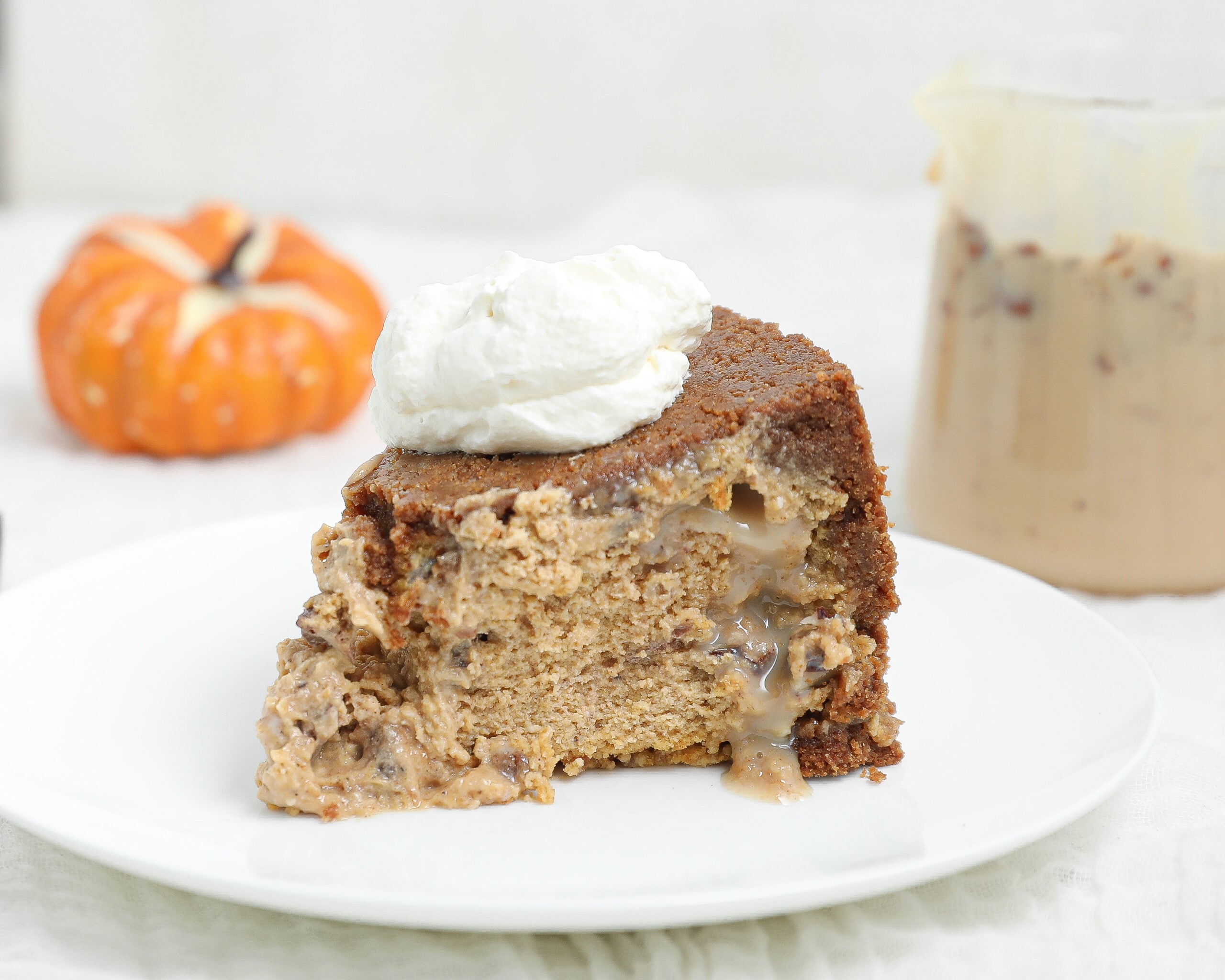 Slice of upside down pecan praline pumpkin cheesecake with a gooey pecan praline center and whipped cream