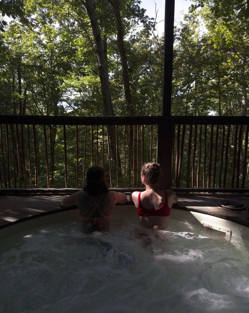 Two guests relaxing in an outdoor hot tub overlooking the trees at Shoji Spa.